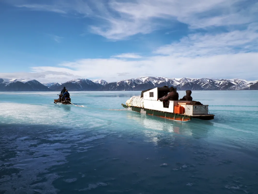 snowmobile pulling a sled on sea ice with melt ponds