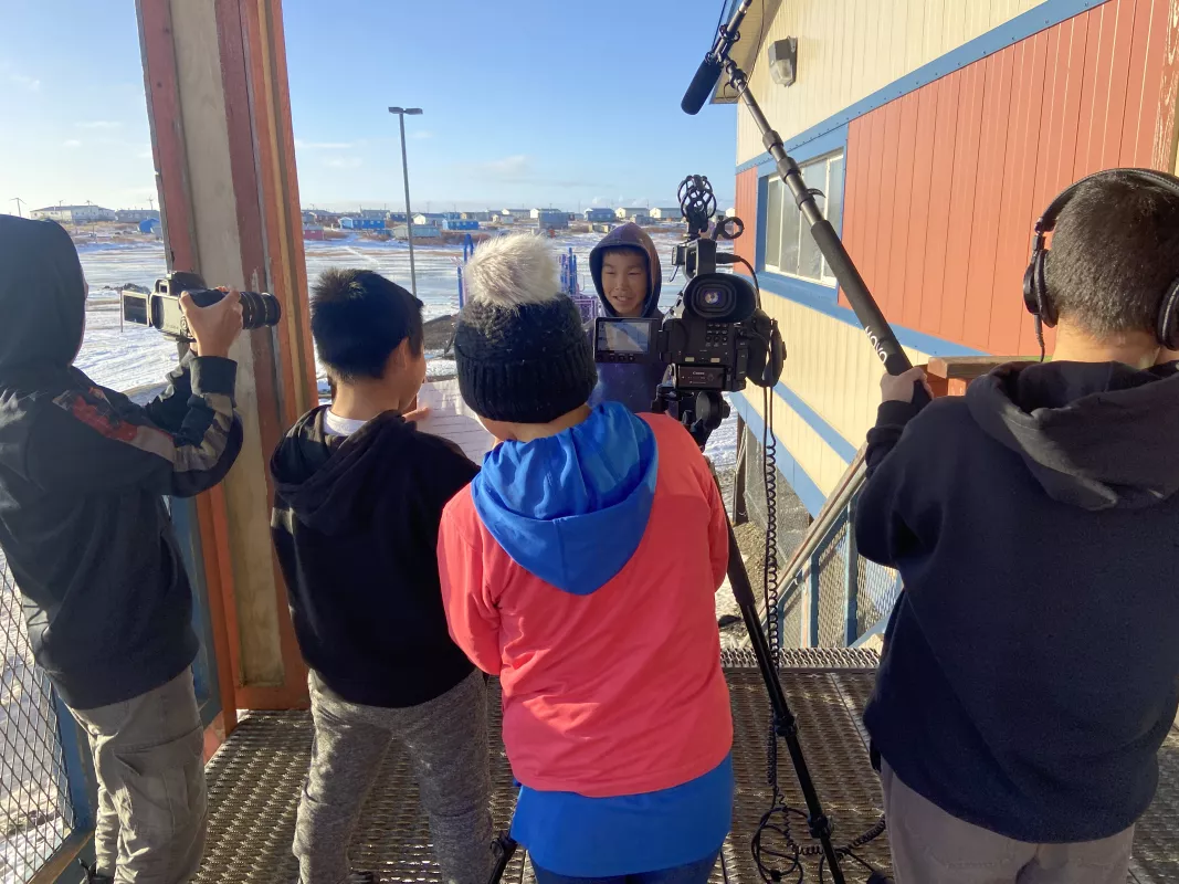 Students practice interviewing each other outside of the school