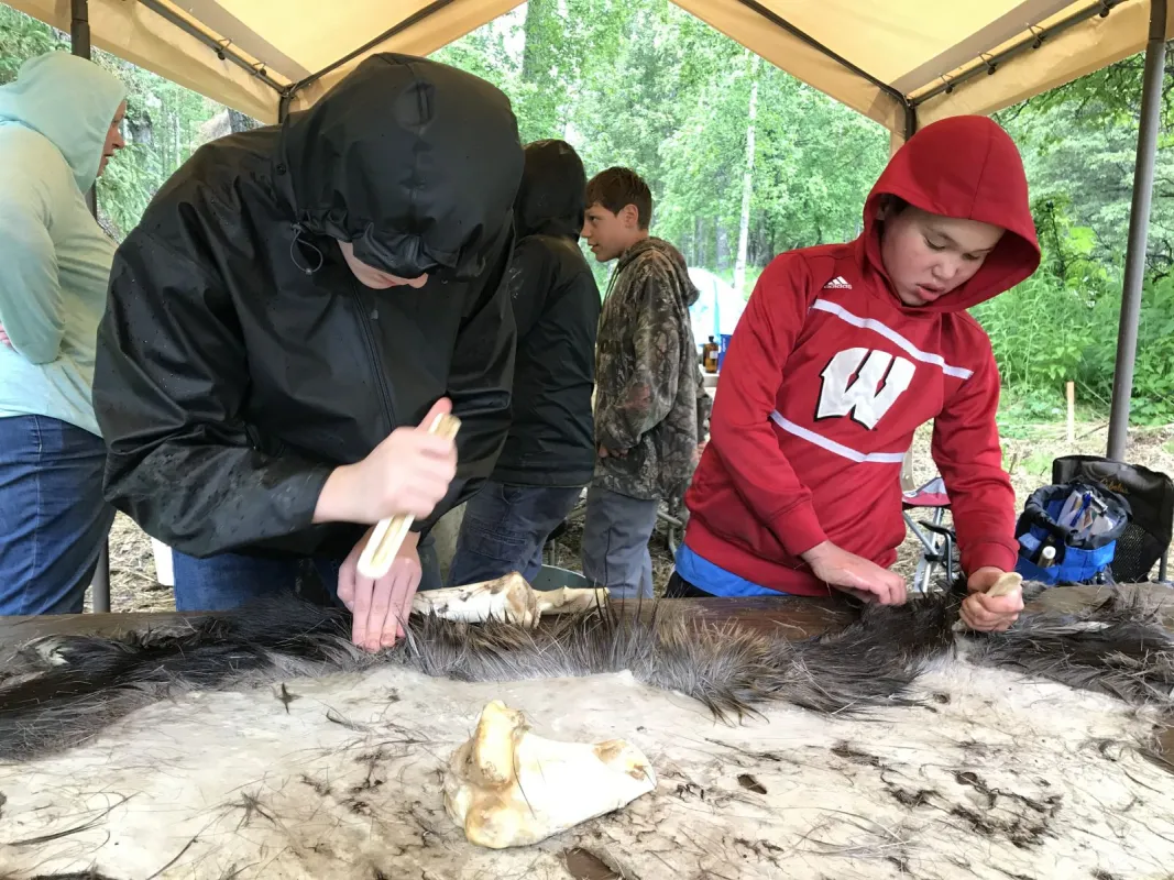 Children scrape a moose hide after learning the proper technique.